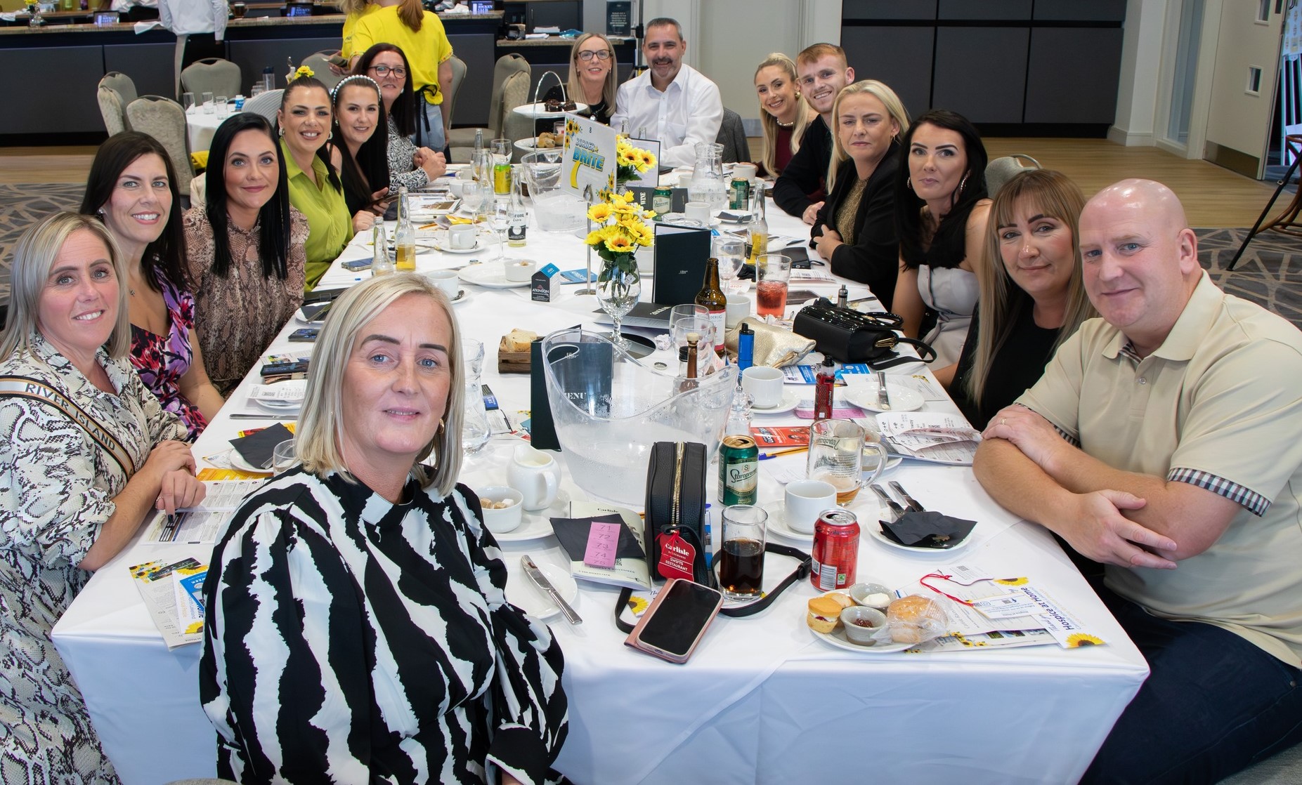 Borderbrite staff group photo at Hospice at Home charity event, seated together at Carlisle Racecourse in support of breast cancer awareness and fundraising
